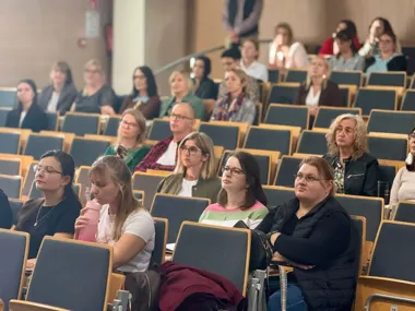 Publiczność, głównie kobiety, siedzi w auli wykładowej i słucha prelekcji.